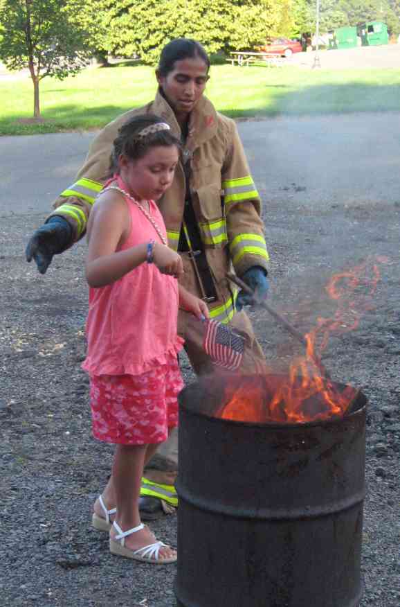 A Great Falls firefigher assists a member of the Providence Society, C.A.R. retire a small worn out flag.