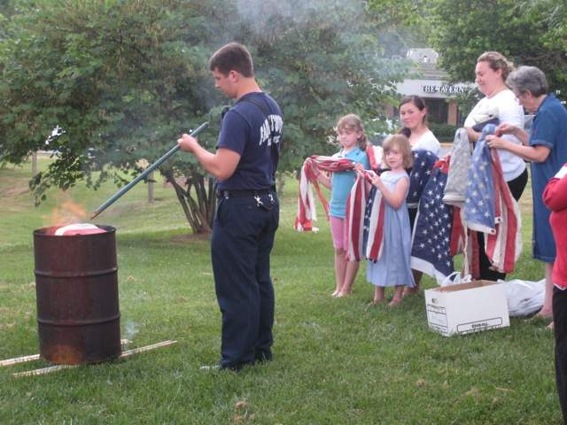 Members of the C.A.R. assist Firefighter Andrew Reedy to retire flags.