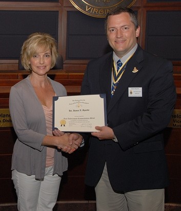 President Dan Rolph presents the Law Enforcement Commendation Medal to Detective James Sparks’ wife Carla.