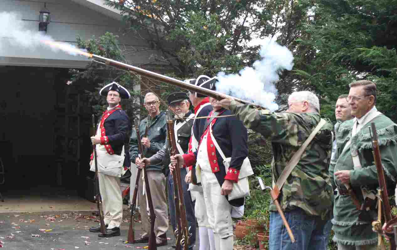 The VASSAR Color Guard look on as Fairfax Resolves Compatriot Vernon Eubanks fires a round from his replica Brown Bess musket.