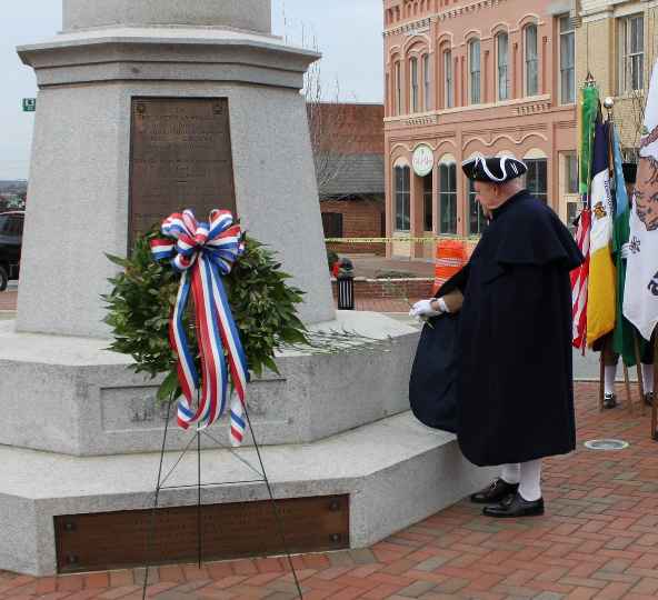 Larry McKinley places the Virginia carnation at the base of the Daniel Morgan Monument.