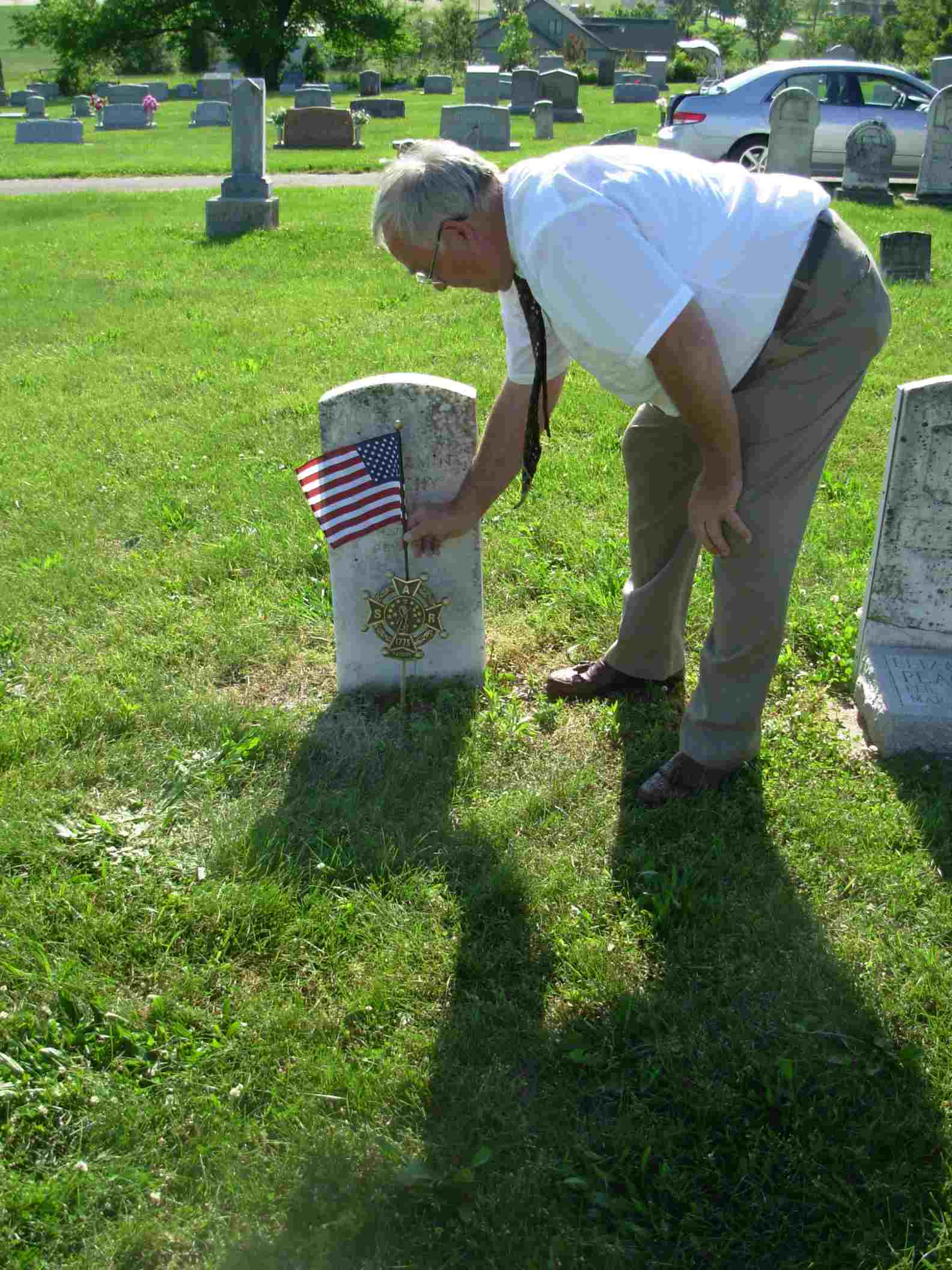 Prospective member Merle Peachee completes the SAR gravemarking of his ancestor Pvt. Benjamin Peachee by placing a flag in the marker.